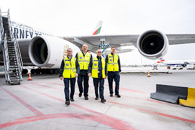 Vier Service Agents gehen vor einem parkenden Flugzeug in Richtung Kamera.