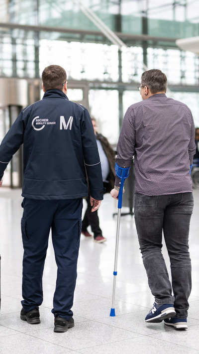 Ein Service Agent begleitet einen Passagier mit Krücken.