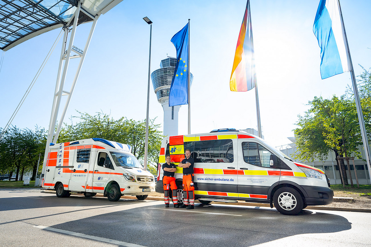 Zwei rettungssanitäter stehen vor zwei Rettungswagen am Flughafen München