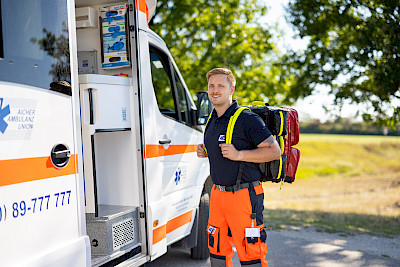 Ein Rettungssanitäter steht vor einem Rettungswagen.