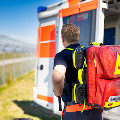 Rettungssanitäter trägt einen Notfallrucksack auf dem Rücken.