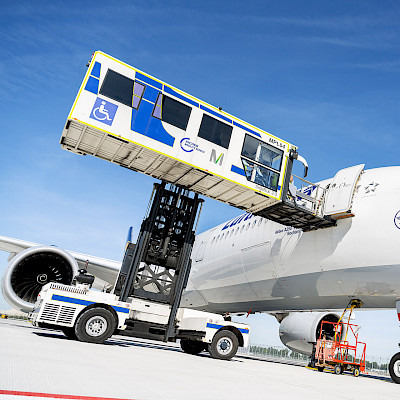 Ein Hublifter hebt eine Reisende im Rollstuhl zur Flugzeugtür.